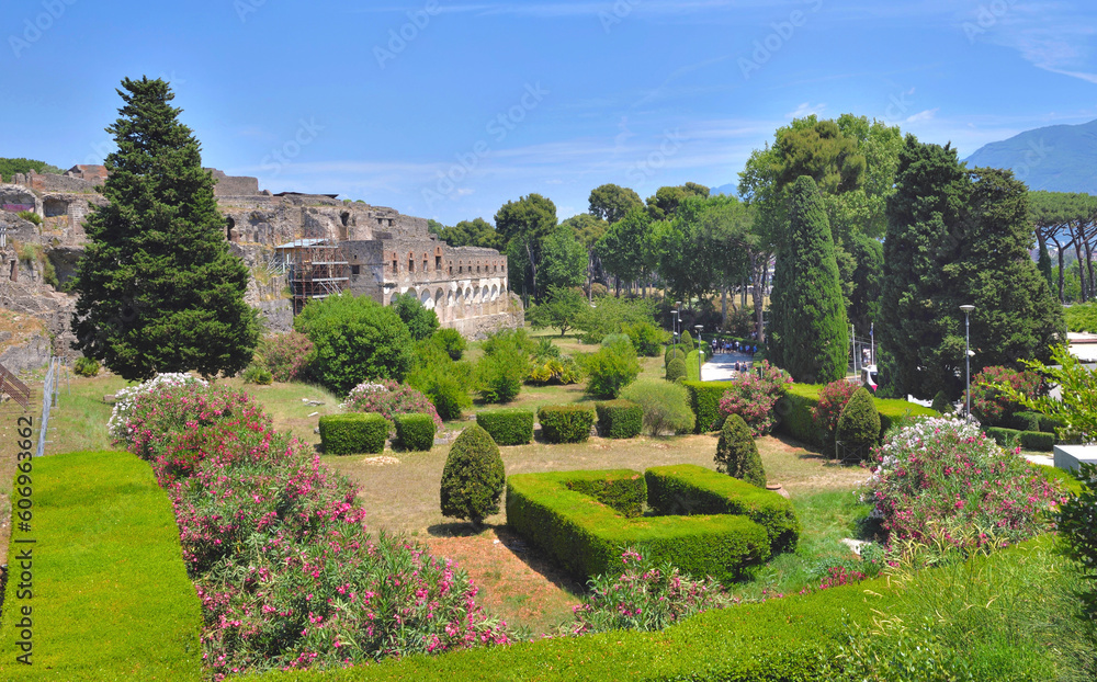 Landscaped garden with cut hedge and trees in the town of Pompeii with the ruins in the background - Italie