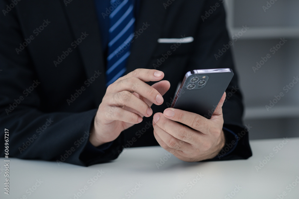 Business man looking at financial information from a mobile phone, he is checking company financial documents, he is an executive of a startup company. Concept of financial management. Business man looking at financial information from a mobile phone, he is checking company financial documents, he is an executive of a startup company. Concept of financial management.