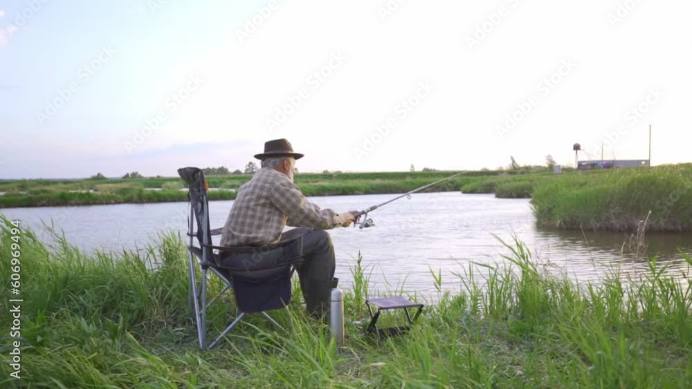 old senior caucasian Man fishing in lake alone, in countryside, Slow motion Back rare view, grandpa catching fish in lake river in nature meditation relaxation resting time old senior caucasian Man fishing in lake alone, in countryside, Slow motion Back rare view, grandpa catching fish in lake river in nature meditation relaxation resting time
