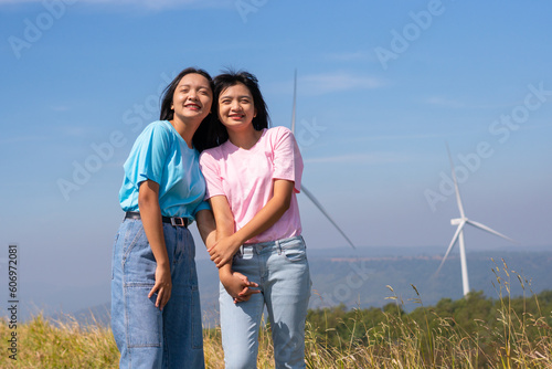 Happy two girls standing together looking at the wind turbines and mountain with blue sky. Khao Yai Thieng Electric Wind Turbine Thailand. photo