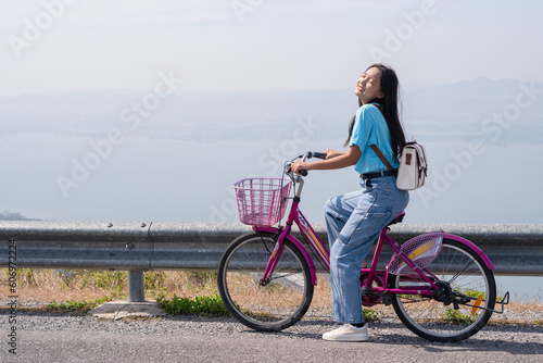 Young girl ride a bike on the road at the mountain with Wind Turbine, Khao Yai Thieng Electric Wind Turbine Thailand. photo