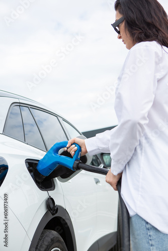 Young business woman refueling her electric car at a EV charging station. Concept of environmentally friendly vehicle. Electric car concept. Green travelling.