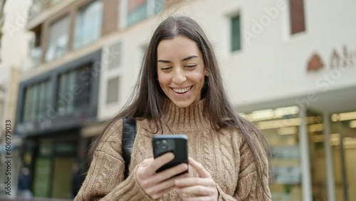 Wallpaper Mural Young beautiful hispanic woman using smartphone smiling at street Torontodigital.ca