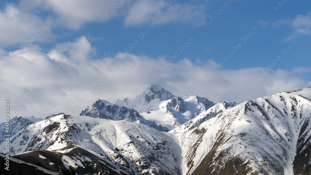 snowy mountain peaks in the clouds. rocks in the snow. cloudy weather in the mountains