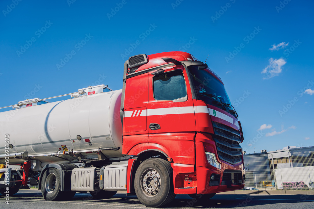 White tanker truck transporting fuel along the road at the blue sky background