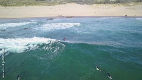 Aerial view of a surfer riding a wave with large beach on background at the Guincho Beach, in Cascais, Portugal
