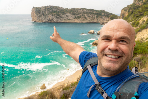 iker man taking a selfie with the sea and cliffs on the background