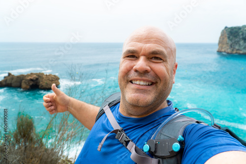 iker man taking a selfie with the sea and cliffs on the background photo