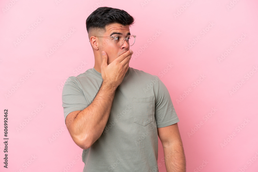 Young caucasian handsome man isolated on pink background doing surprise gesture while looking to the side Young caucasian handsome man isolated on pink background doing surprise gesture while looking to the side