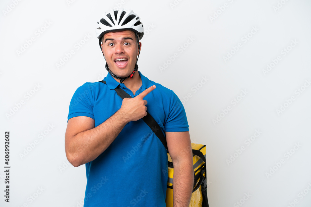 Young caucasian man with thermal backpack isolated on white background surprised and pointing side Young caucasian man with thermal backpack isolated on white background surprised and pointing side
