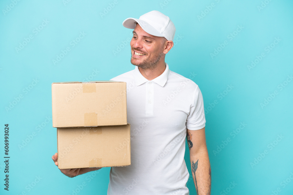 Delivery caucasian man isolated on blue background looking to the side and smiling Delivery caucasian man isolated on blue background looking to the side and smiling