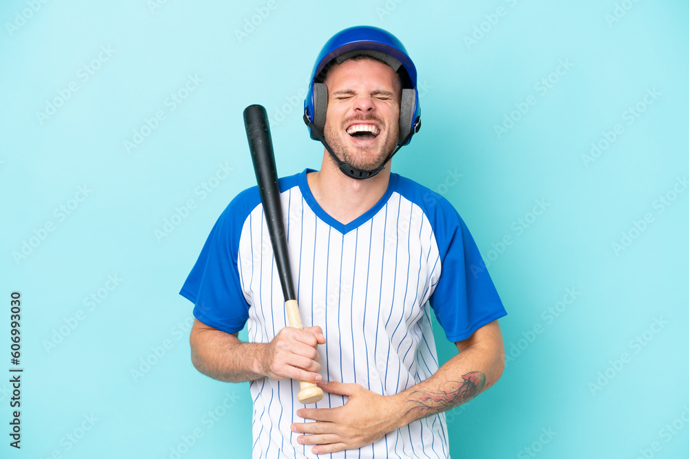 Baseball player with helmet and bat isolated on blue background smiling a lot Baseball player with helmet and bat isolated on blue background smiling a lot