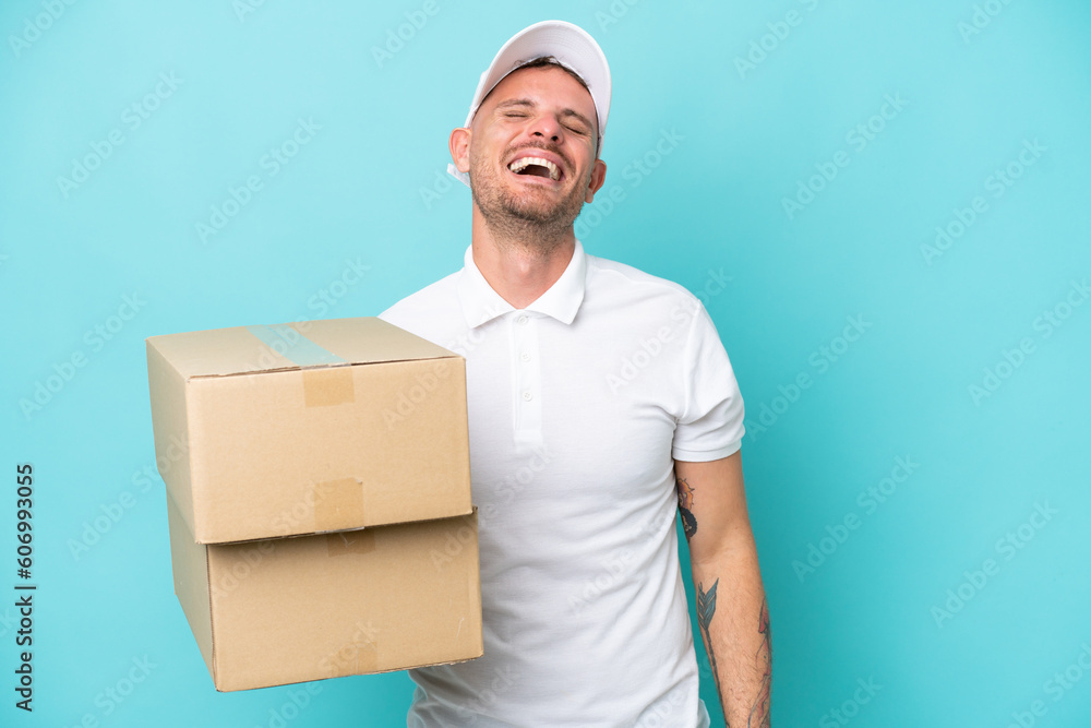 Delivery caucasian man isolated on blue background laughing Delivery caucasian man isolated on blue background laughing