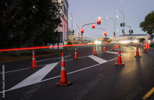 Obraz na płótnie Orange traffic cones lined up on the road. Car light trails on the road intersection. Auckland. w salonie