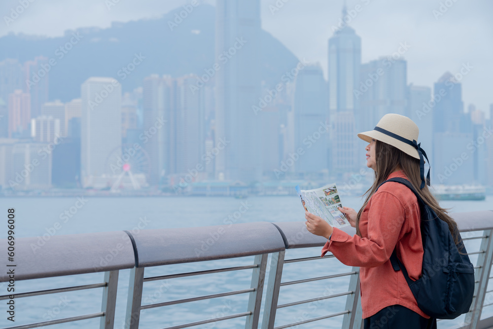 Asian tourist, cute woman with long hair are traveling in Hong Kong along with map and her camera with fun on her holiday,traveler relaxing and enjoying at Victoria harbour in Hong Kong. Asian tourist, cute woman with long hair are traveling in Hong Kong along with map and her camera with fun on her holiday,traveler relaxing and enjoying at Victoria harbour in Hong Kong.
