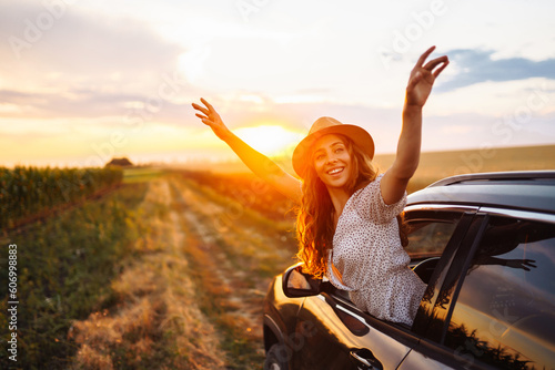 Young woman is resting and enjoying sunset in the car. Woman on the road trip. ifestyle, travel, tourism, nature, active life.