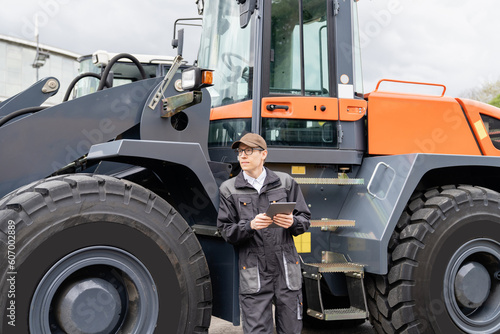 Serviceman with digital tablet on a background of the tractor  © scharfsinn86