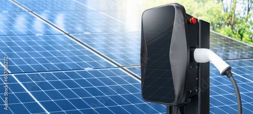 Close up of electric car charging station on the background of solar panels