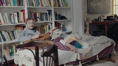 Wallpaper Mural Young loving couple resting on bed, boy playing the guitar and girl lying down by his legs and listening to the music. Full shot Torontodigital.ca