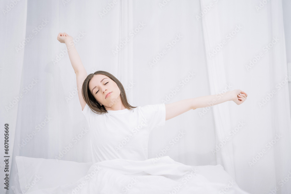 Woman is waking up and stretching in the bed in her bedroom. Woman is waking up and stretching in the bed in her bedroom.