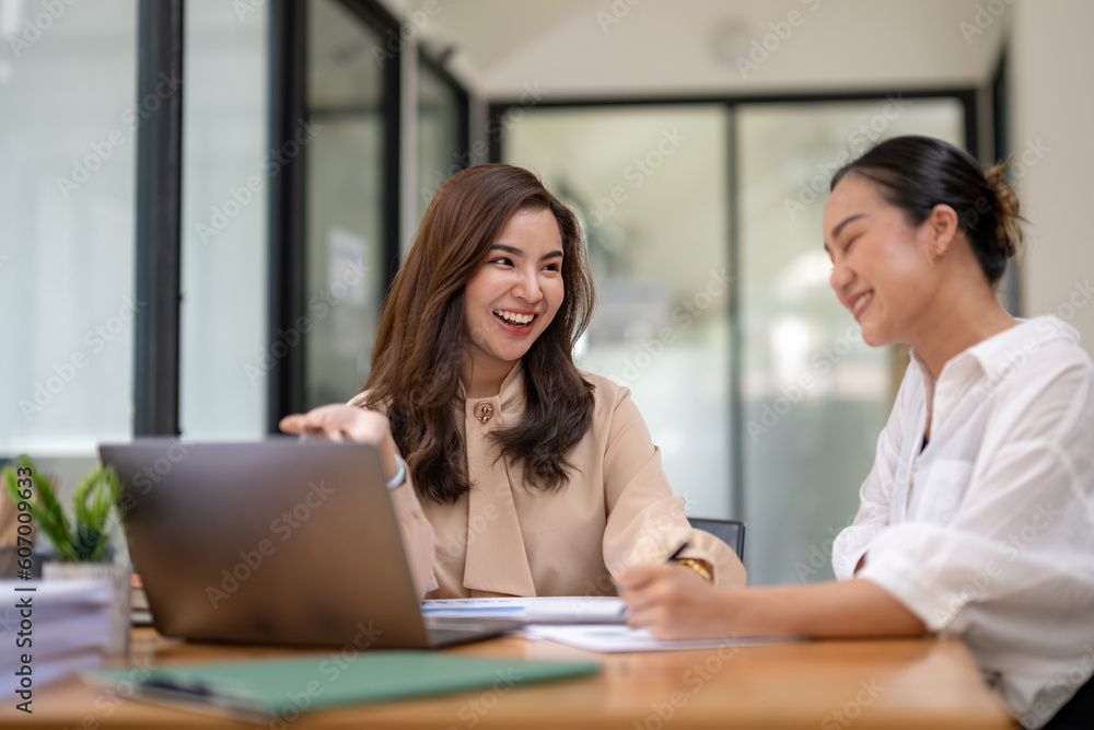 Two business women sit and discuss plans for a new project. Brainstorm and share ideas.