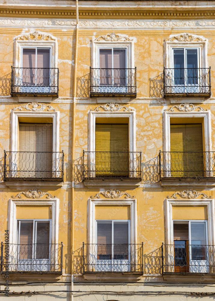 Windows and balconies on a historic yellow house in Teruel, Spain