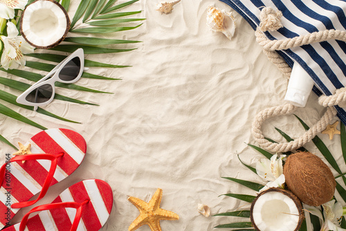 Fototapeta Naklejka Na Ścianę i Meble -  Transport yourself to sunny realm of summer relaxation with top view scene: glasses, beach bag, flip-flops, sunscreen, shell, starfish, palm leaves, coconut, flowers. Sandy shore, space for text or ad