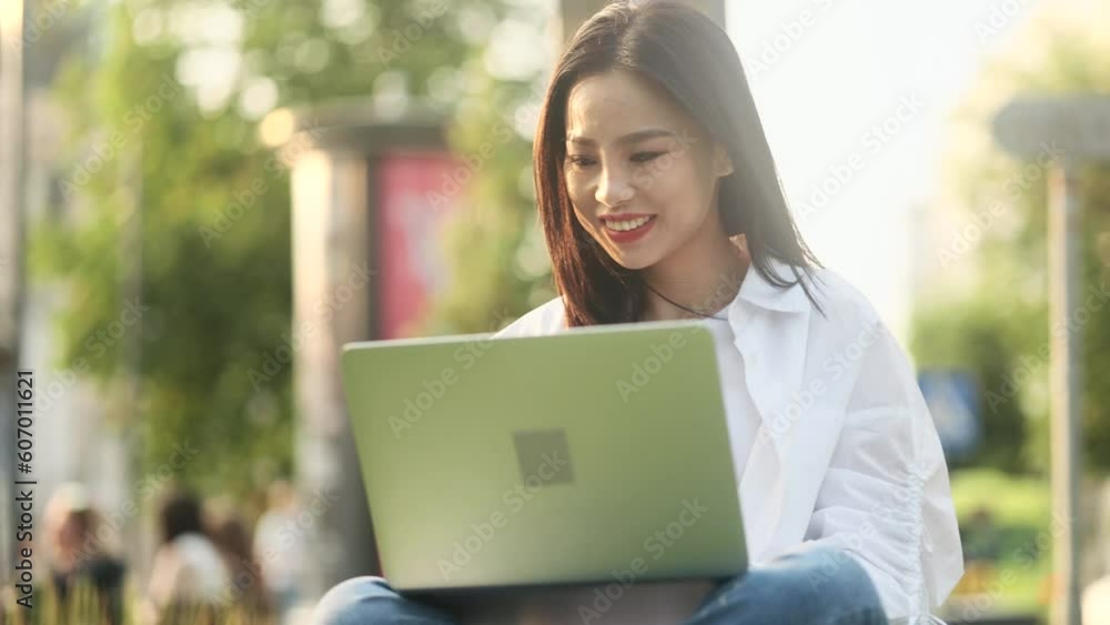 Pretty young asian woman freelancer or student working on laptop at green city street Busy focused girl having distance remote freelance work or education on computer outdoors alone Pretty young asian woman freelancer or student working on laptop at green city street Busy focused girl having distance remote freelance work or education on computer outdoors alone