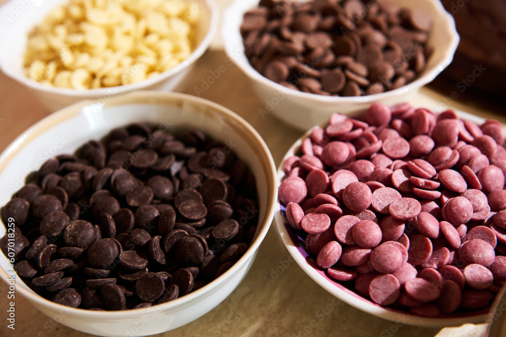 Dark, milk, white and ruby pink chocolate chips in bowls on marble kitchen countertop background. Food background. Still life Dark, milk, white and ruby pink chocolate chips in bowls on marble kitchen countertop background. Food background. Still life