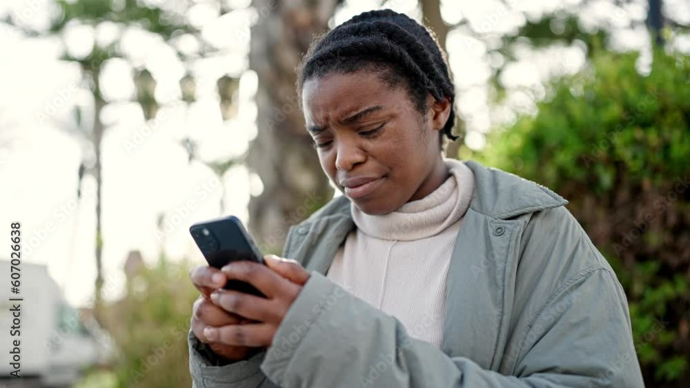 African american woman using smartphone with serious expression at park African american woman using smartphone with serious expression at park