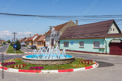 A fountain on a beautiful street with historic houses in the city of Greenbow. Transylvania. Romania photo