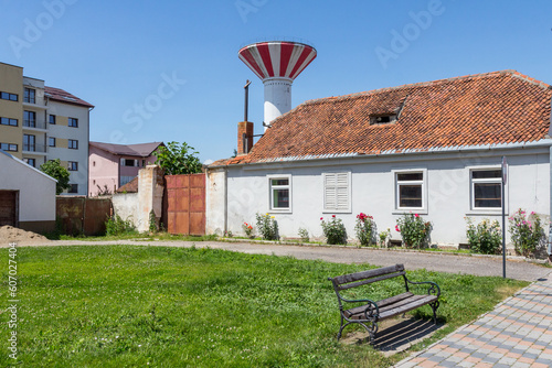 A view of a wooden bench and a water tower next to a historic house in the town of Greenbow. Transylvania. Romania photo