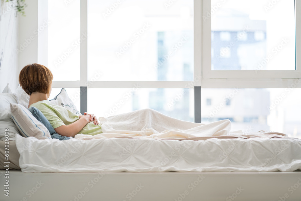 Tired woman sleeping on the bed in front of the window Tired woman sleeping on the bed in front of the window