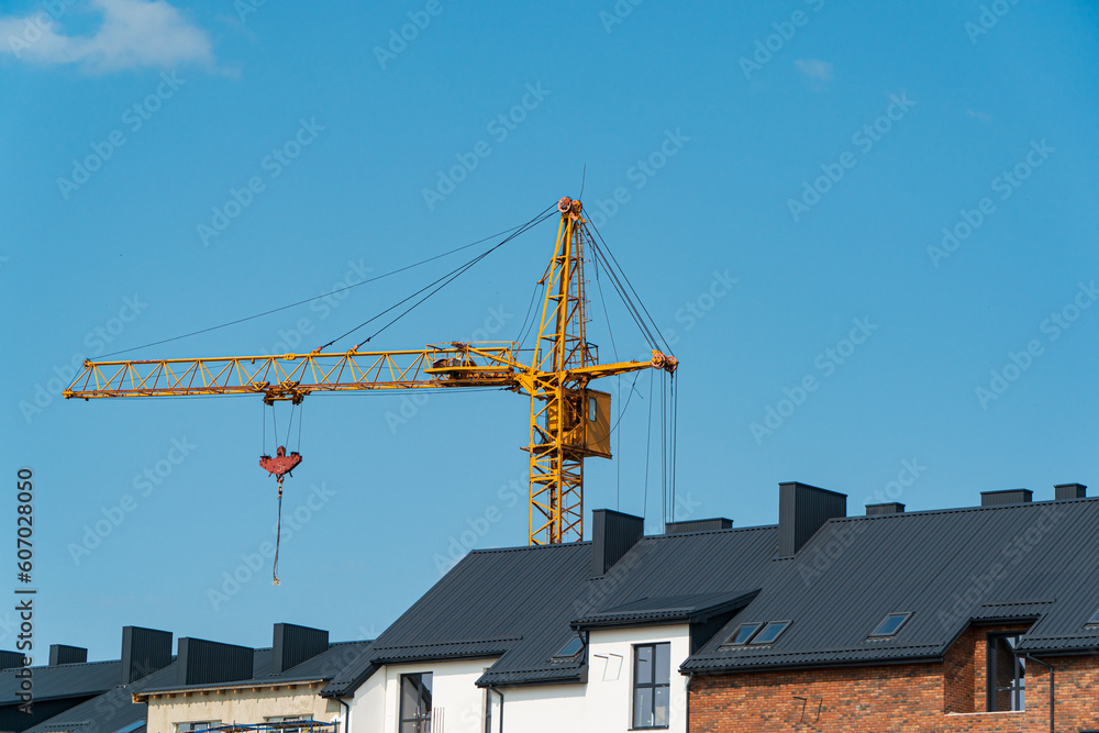 Yellow construction crane on the background of residential buildings
