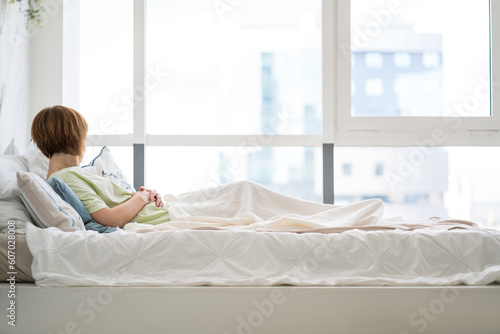Tired woman sleeping on the bed in front of the window