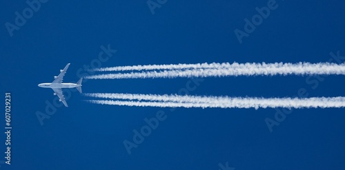 Fotografía White aircraft at a distance and contrails in clear blue sky