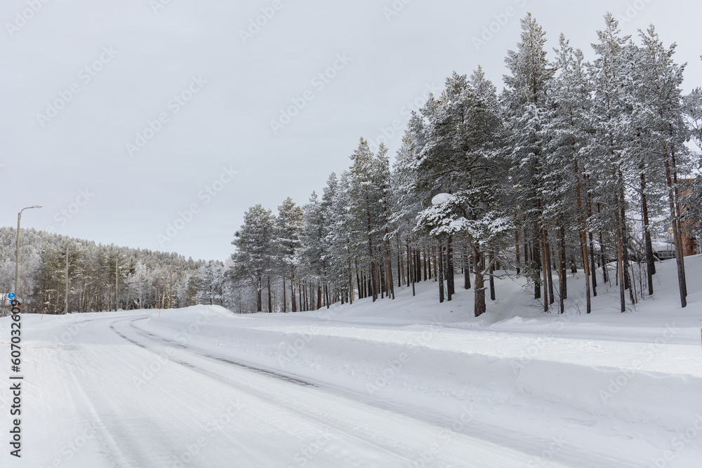 Snow covered icy curved road with birch trees in Lapland, Finland Snow covered icy curved road with birch trees in Lapland, Finland