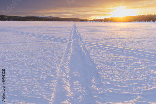 Sunset over the frozen Ounasjärvi lake with surrounding pine forests and hills in the background in Hetta, Lapland, Finland photo