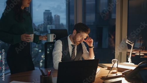 Woman bringing coffee colleague working together in office late evening.