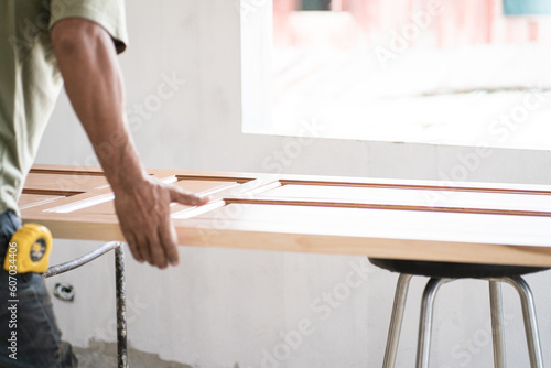 Carpenter man working with teak wooden door installation