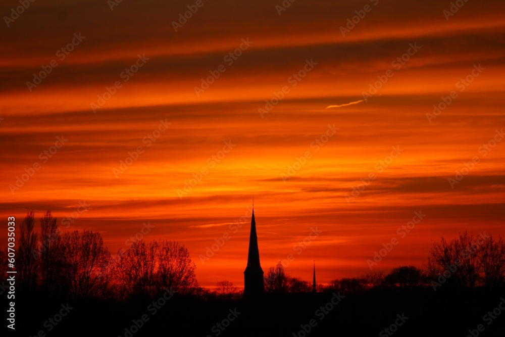 Silhouette shot of a tower with a bright red sunset sky in the background