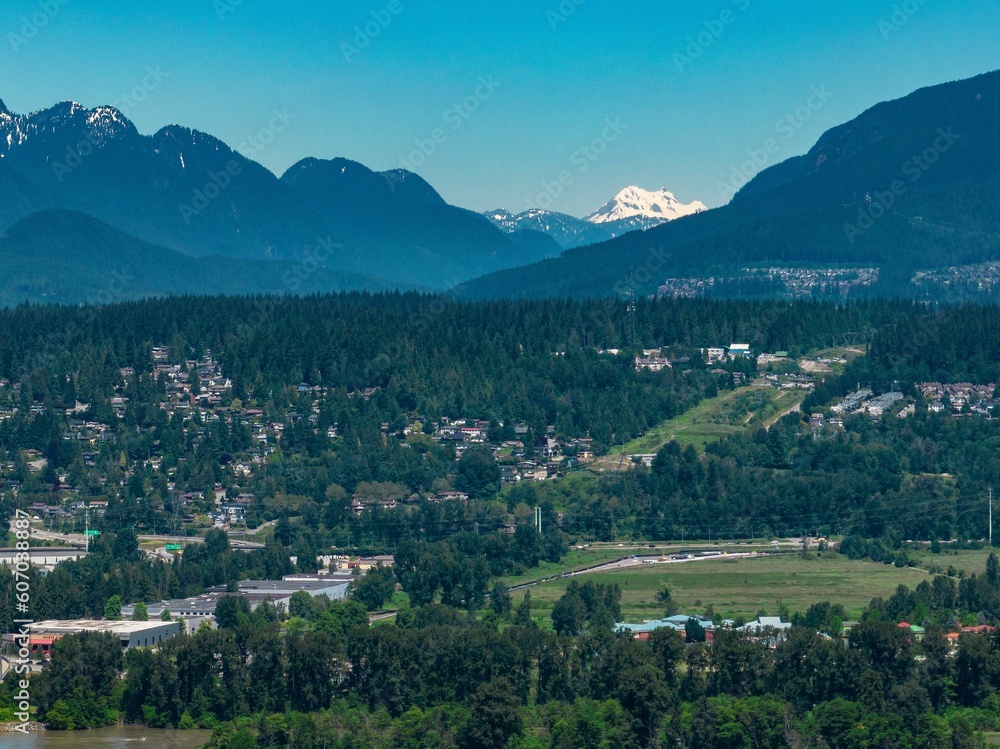 Drone shot of Coquitlam cityscape with greenery and mountain in the background