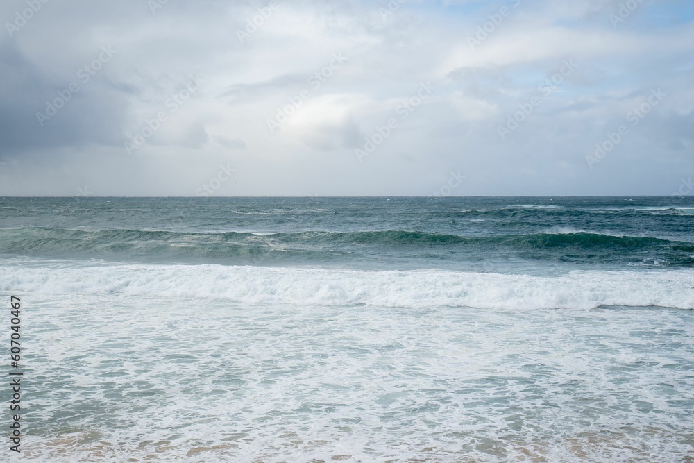 Beautiful scenery of beach with waves under a cloudy sky - great for wallpapers