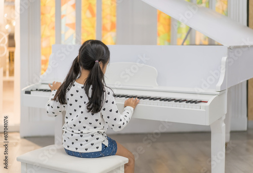 back asian child cute or kid girl musician and happy playing white piano or vintage electone to song show on stage or people learning at music school for artist education and instrumental music study