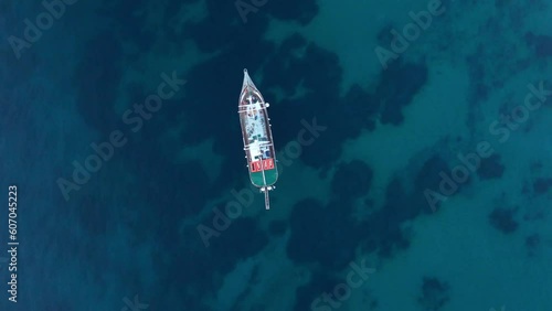 Aerial drone Birds Eye view video of boat on bright blue ocean photo