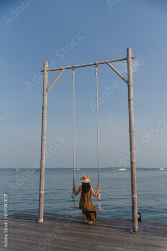 Lonely woman sit at swing to sightseeing seascape on vacation
