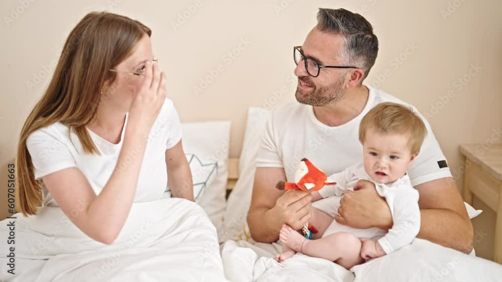 Family of mother, father and baby together sitting on the bed at bedroom Family of mother, father and baby together sitting on the bed at bedroom