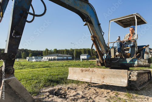 Young man operating his old excavator during his work on a construction site