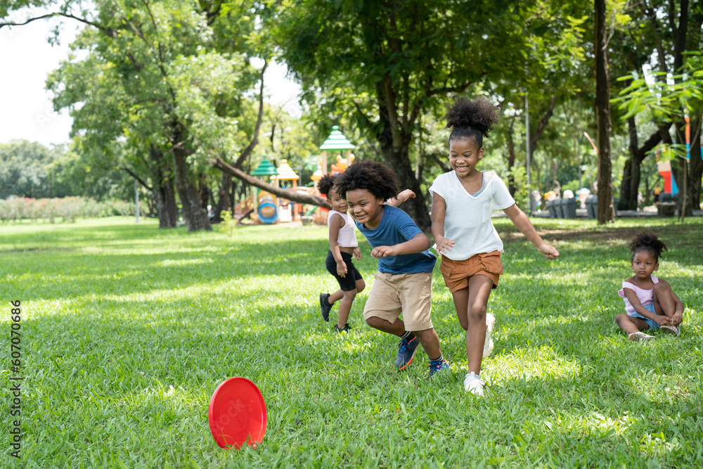 Φωτογραφία Group kids African American little girls and boys have fun playing and throwing red flying disc in the park