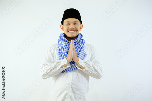 Handsome Moslem Asian man smiling while doing hand praying gesture. Ramadan or ied concepts. photo